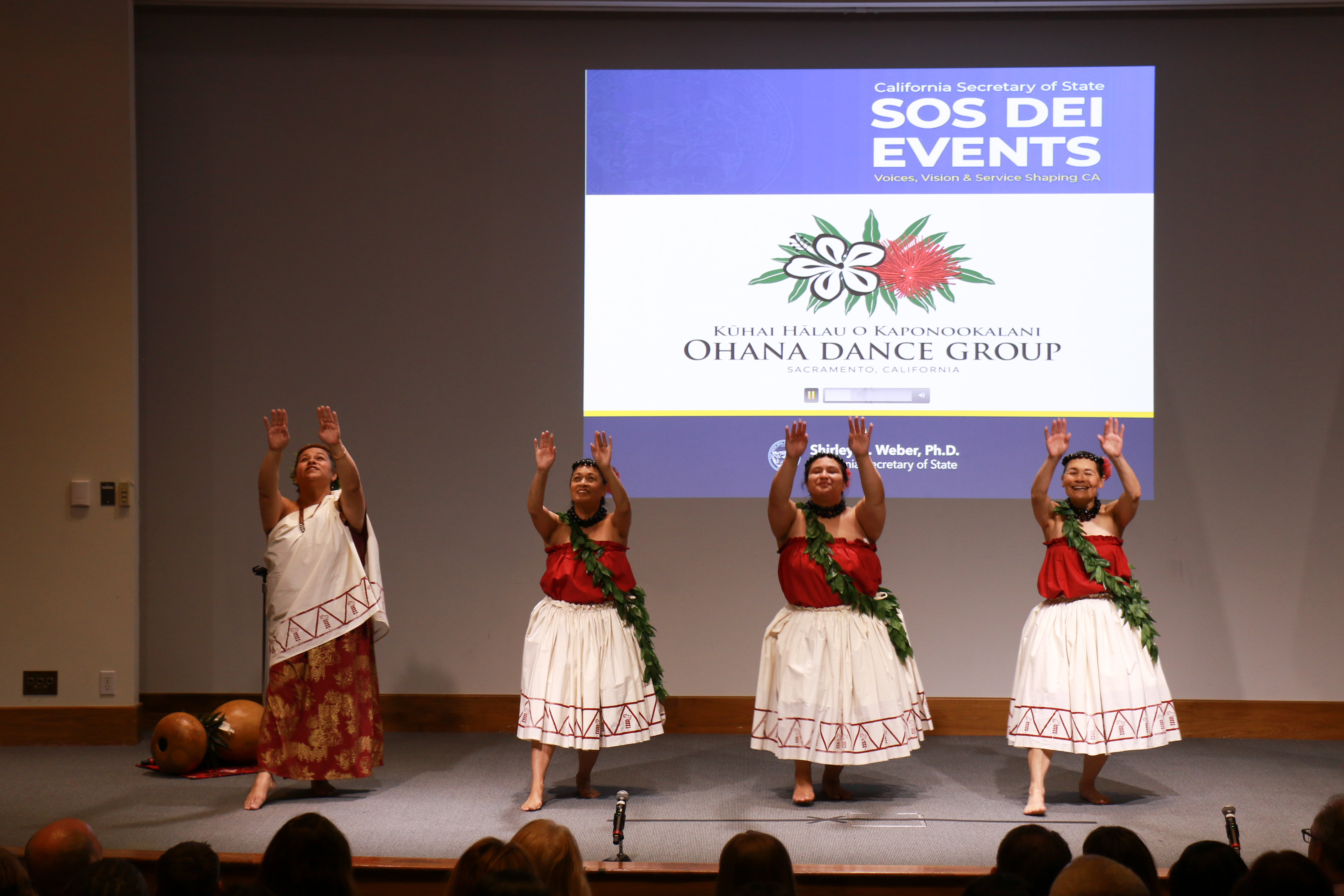 Four dancers perform on stage, facing the audience.