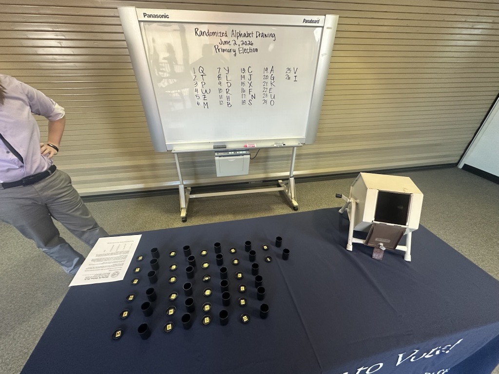Randomized Alphabet Drawing event. There is a table with drawn numbers and a whiteboard with the written draw numbers.